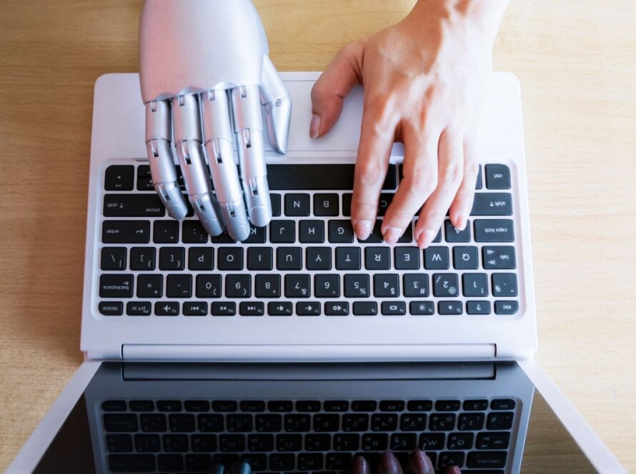 a left human and right robot hands typing on a laptop keyboard represents AI and Human